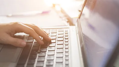 Hand auf Notebook-Tastatur Hand auf Notebook-Tastatur