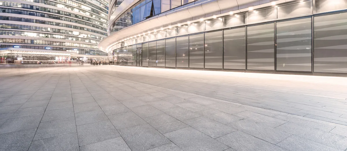 Moderne Glasfassade mit beleuchtetem Vorplatz bei Nacht Moderne Glasfassade mit beleuchtetem Vorplatz bei Nacht