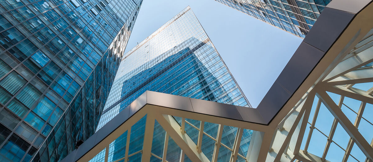 DZ HYP sees itself as a subsidiary service provider for the Volksbanken Raiffeisenbanken Cooperative Financial Network. A woman and a man in business attire stand on a large, bright staircase of an office building, smiling and shaking hands